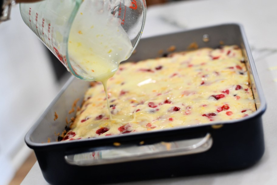 pouring orange glaze over cranberry cake