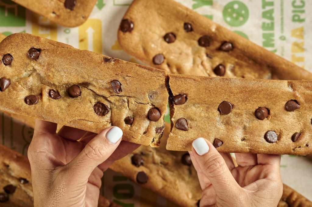 hands breaking a foot-log cookie in half