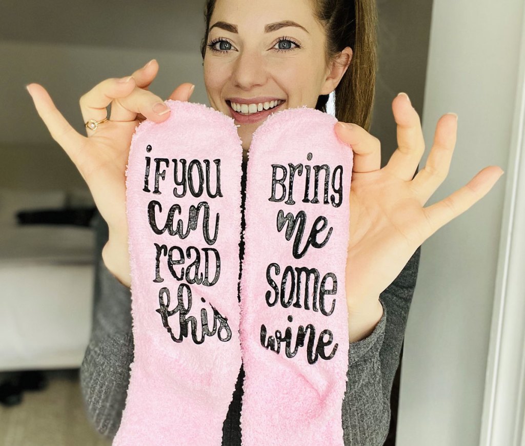 woman holding up pair of pink fuzzy socks