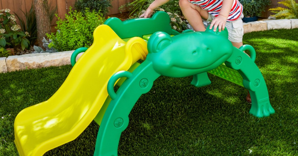 boy playing on frog climber in backyard