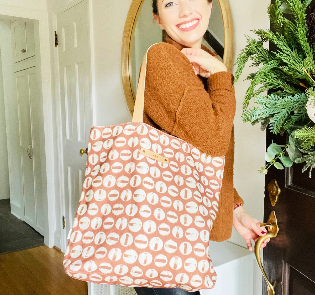 woman opening door with tote bag on shoulder