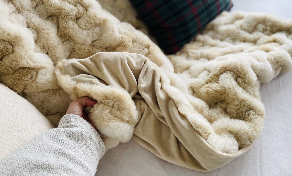 hand holding corner of faux fur on white couch