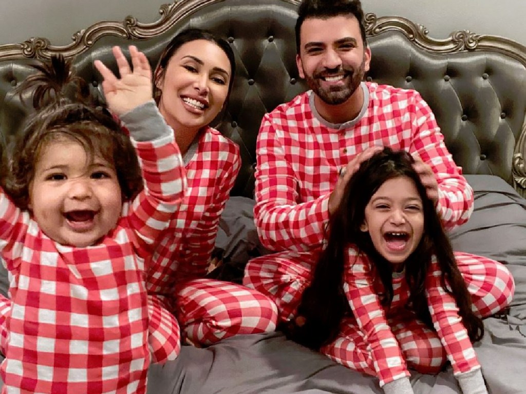 family sitting on bed together smiling