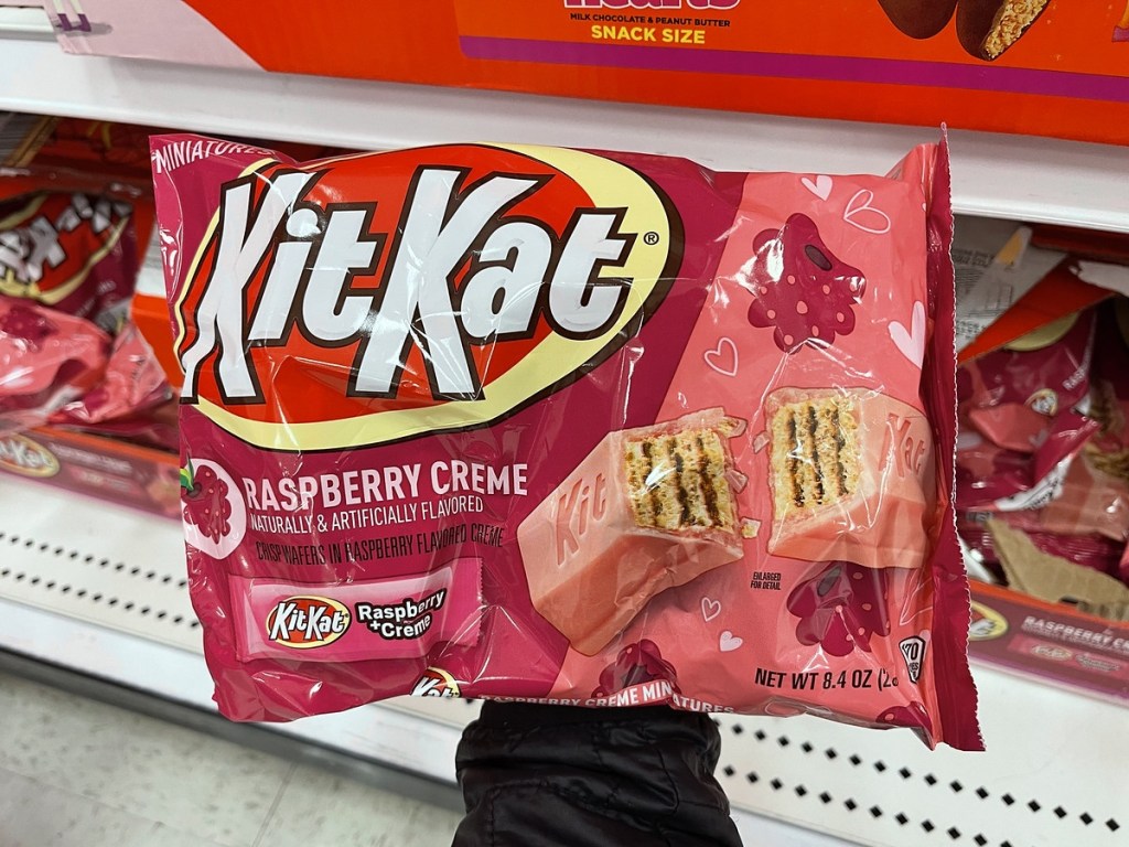 holding a bag of raspberry kit kats