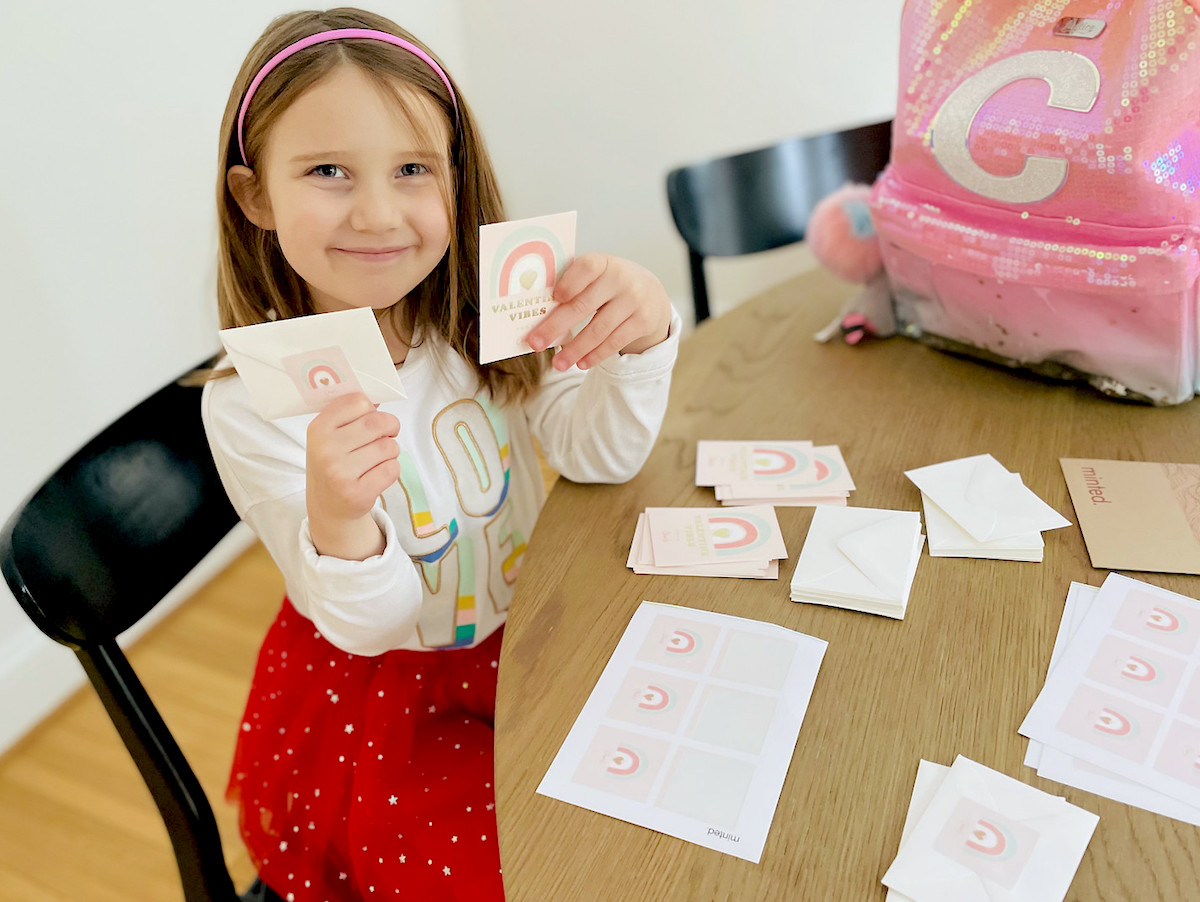 girl sitting at table holding up rainbow cards