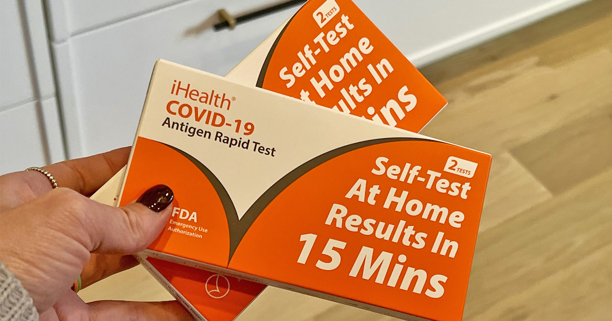 hand holding boxes of covid home test kits
