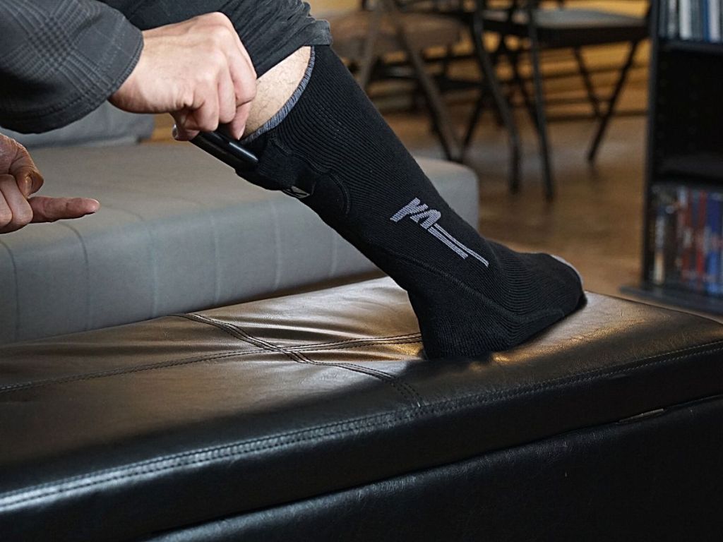 man wearing Kemimoto Heated Socks putting battery pack in