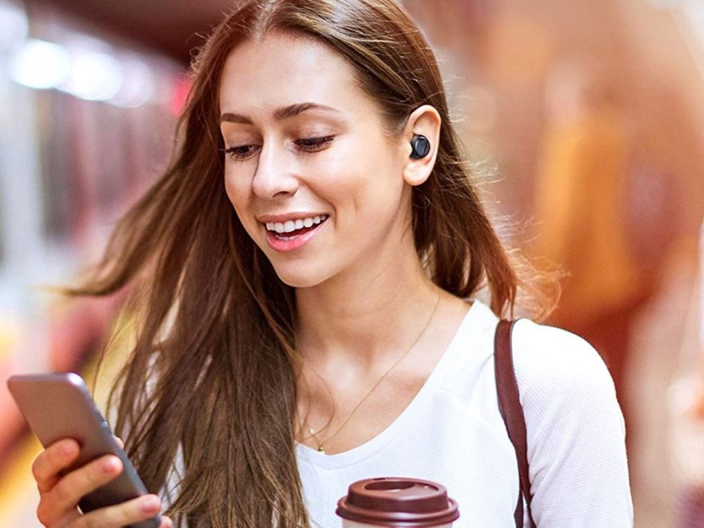 woman wearing black Taotronics earbud looking at phone