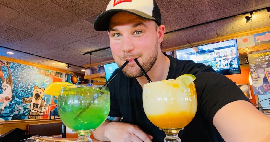 man drinking from two cocktails from Applebees for their St. Patrick's Day deals