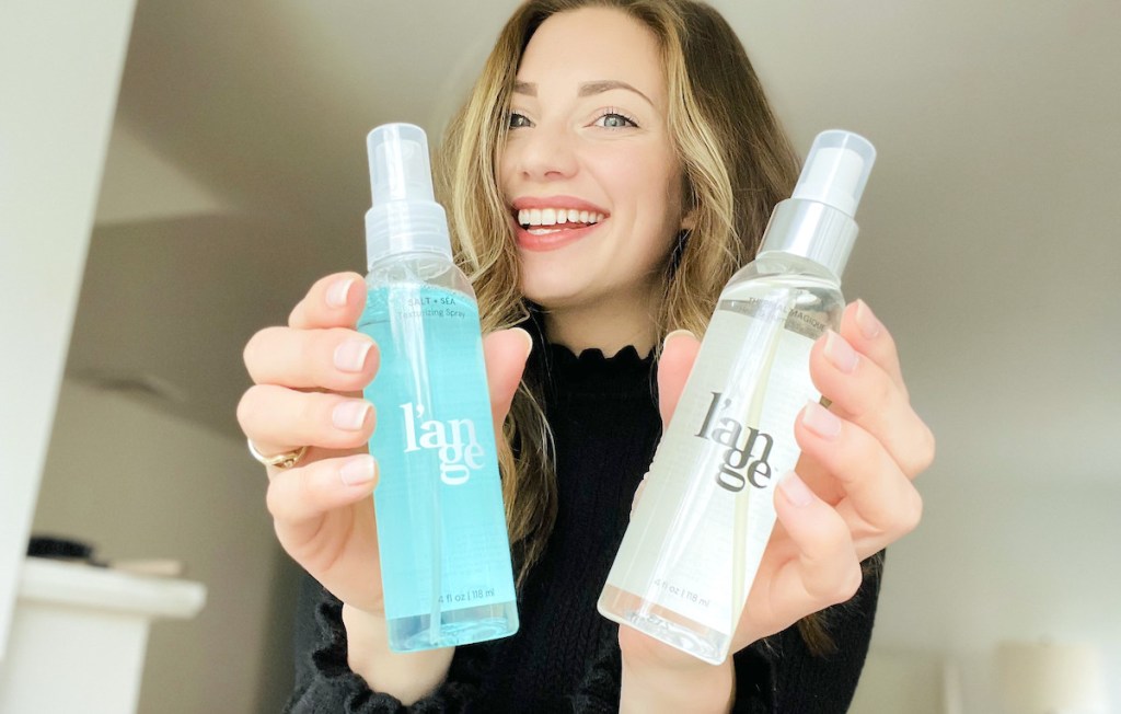 woman holding two bottles of lange hair products smiling