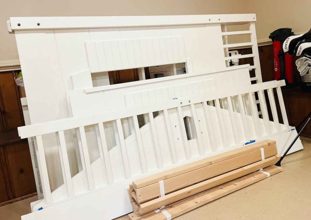 white bed pieces standing in pile on floor