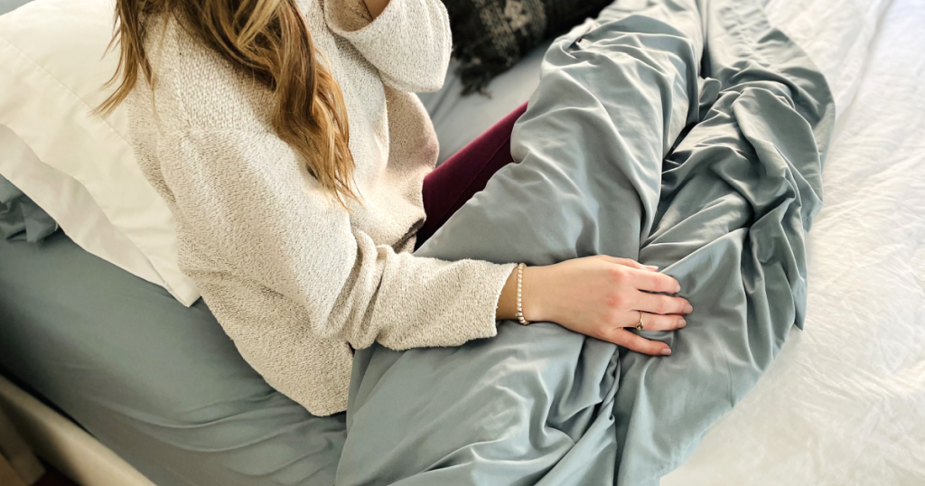 woman in bed wrapped in Walmart bedsheets 