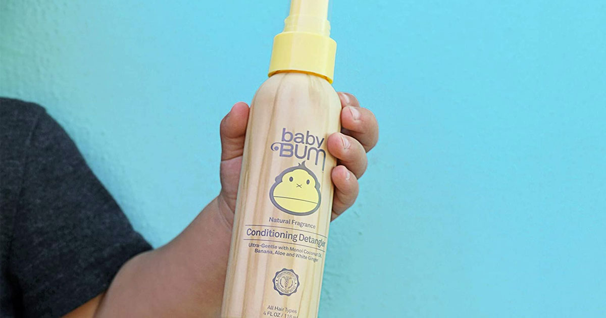 child holding bottle of Baby Bum Conditioning Detangler Spray