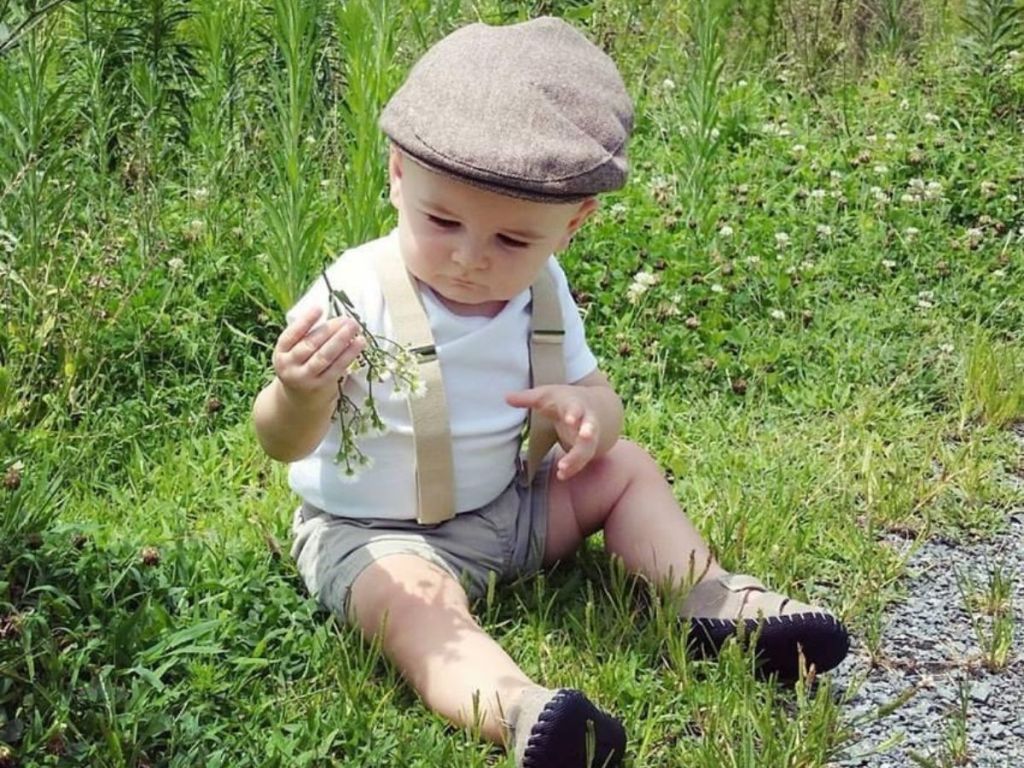 little boy wearing suspenders and driver cap