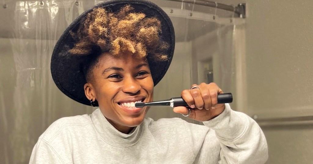 woman using a black electric toothbrush