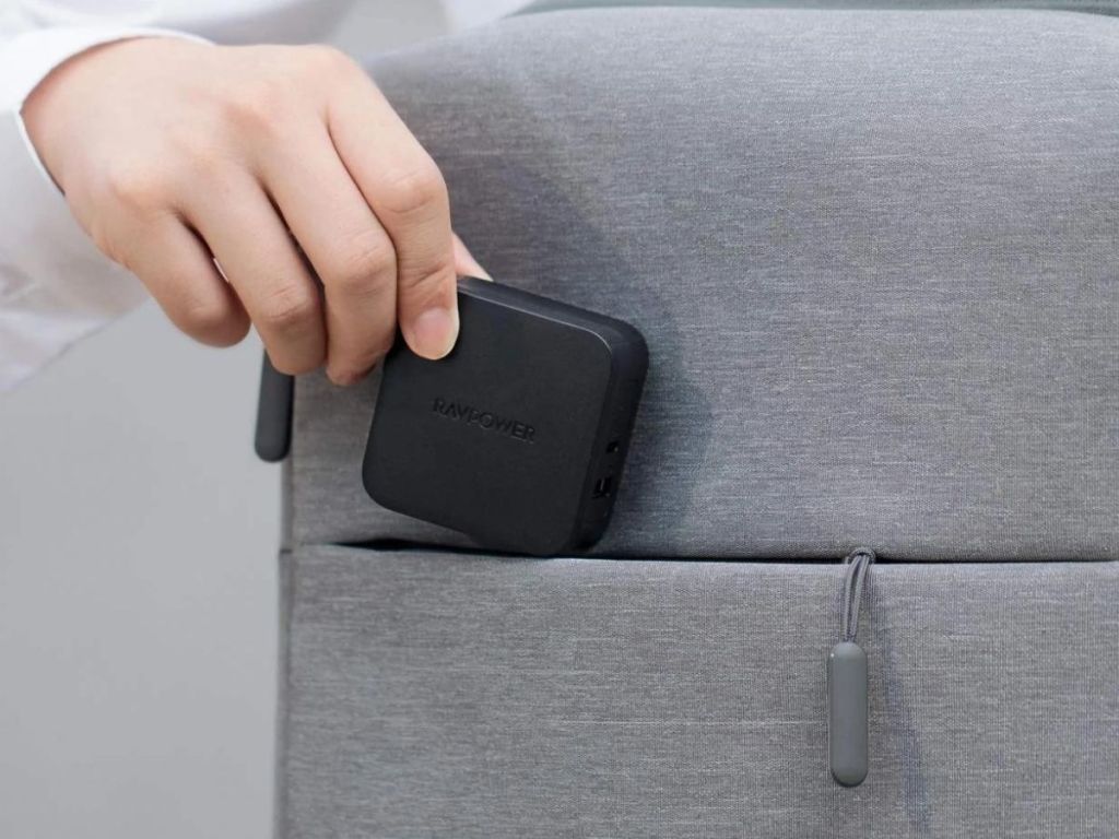 hand putting RAVPower Pioneer 61W 2-Port USB C Wall Charger into laptop bag