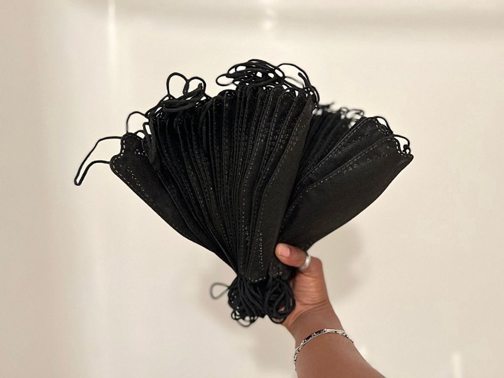 hand holding stack of black face masks