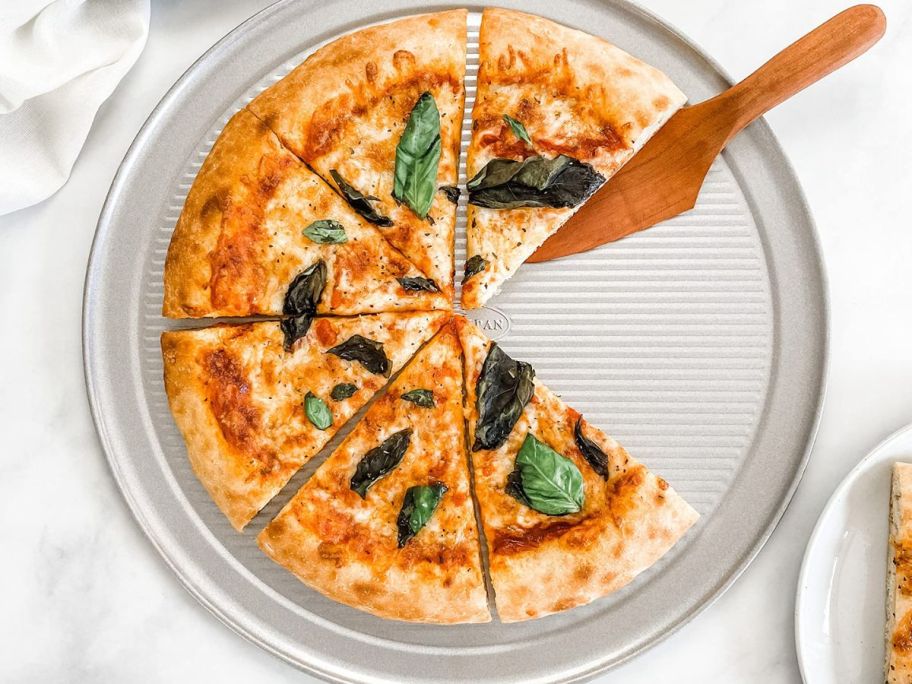 A USA Pan Bakeware 14" Pizza Pan with a pizza on it