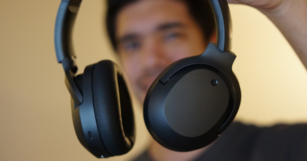 man holding up a pair of black headphones