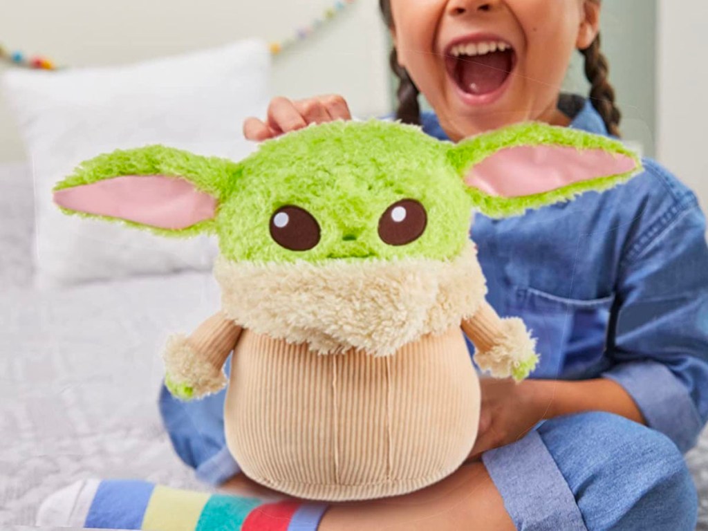 child playing with grogu plush toy