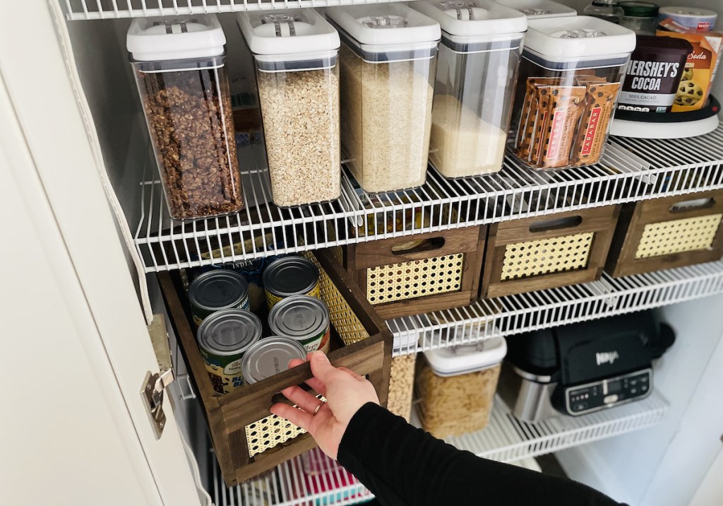 hand pulling out rattan and wood crate from organized pantry