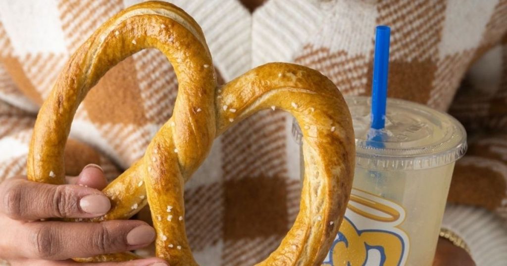 woman holding a pretzel and a drink