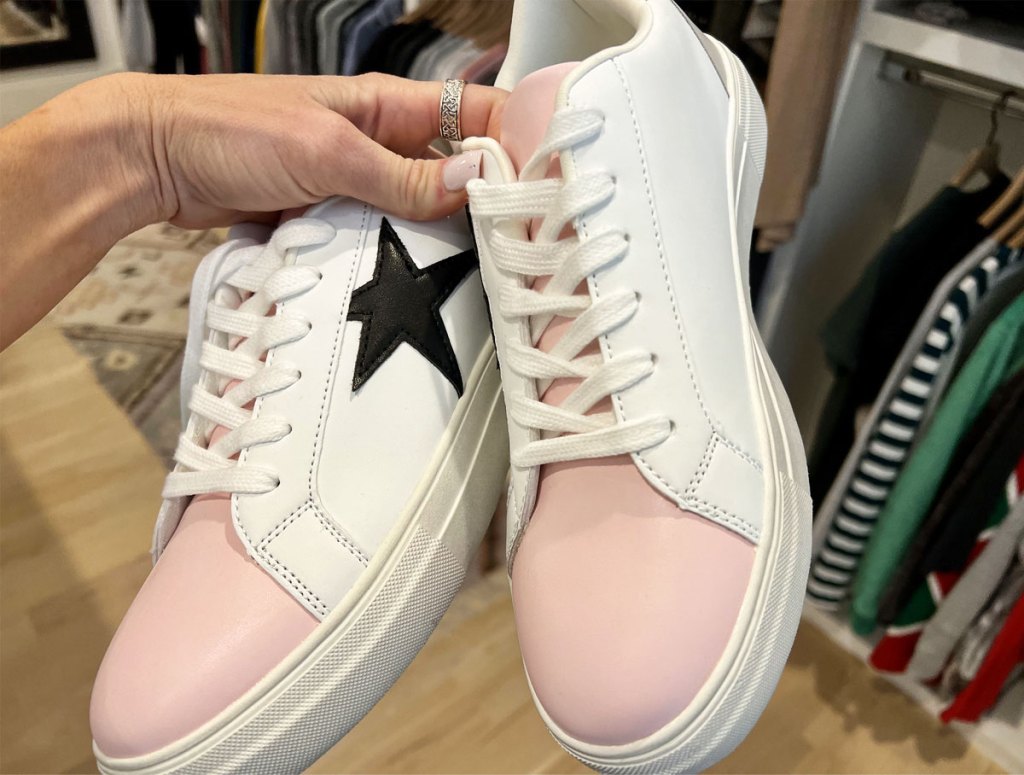 hand holding pair of white and pink sneakers