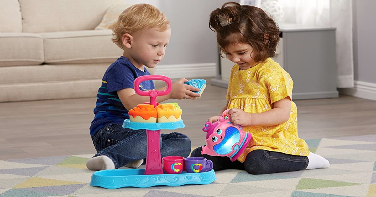 two kids on the floor playing with a tea party set