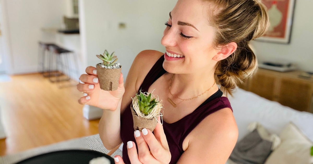 woman holding two baby succulent plants smiling