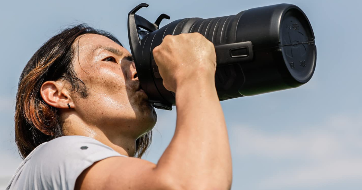 man drinking from a large Under Armour water jug