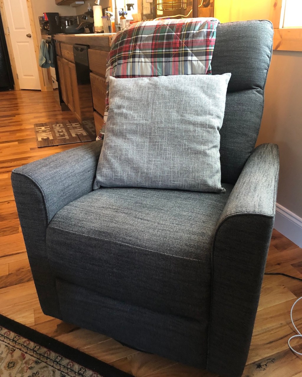 glider chair with throw pillow and plaid blanket