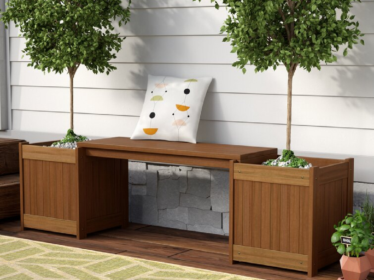 fallah wooden planter bench with trees planted in it and a throw pillow on it