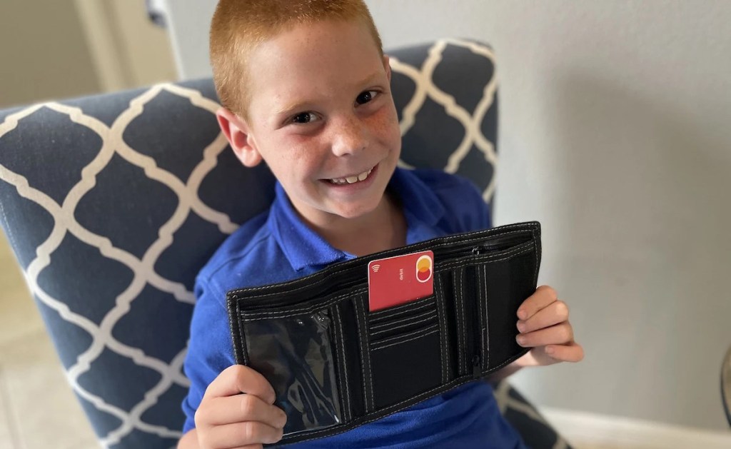 young boy holding gohenry debit card for kids