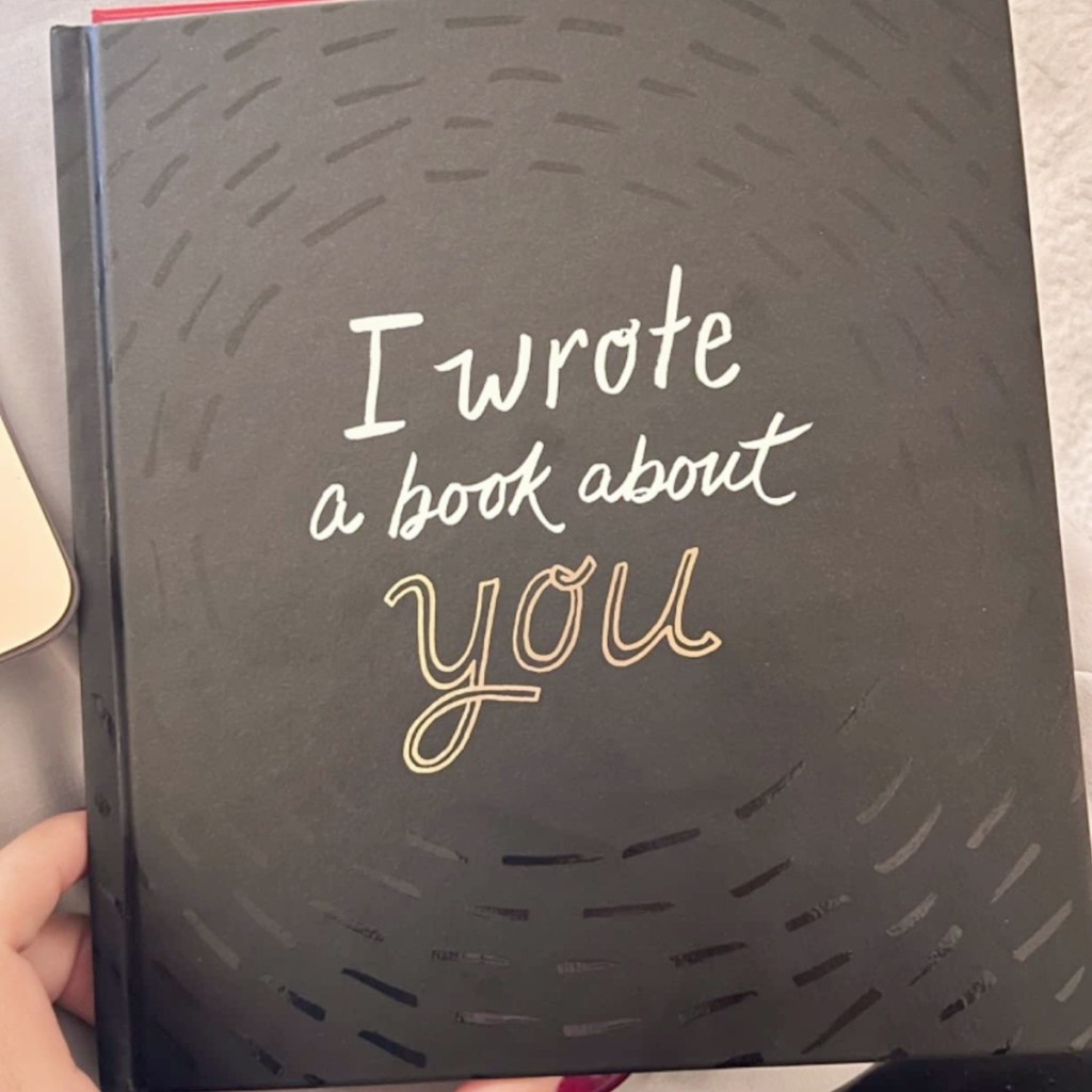 holding a book with the words "I wrote a book about you" on the cover