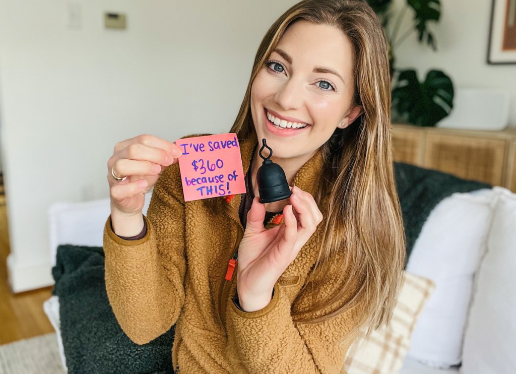 woman holding menstrual cup with added savings on pink post it note