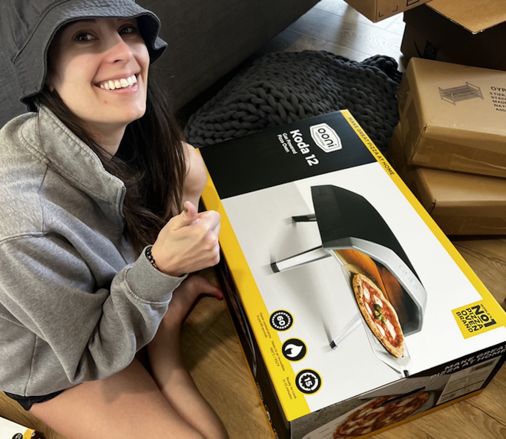 woman giving thumbs up holding ooni pizza cooker box