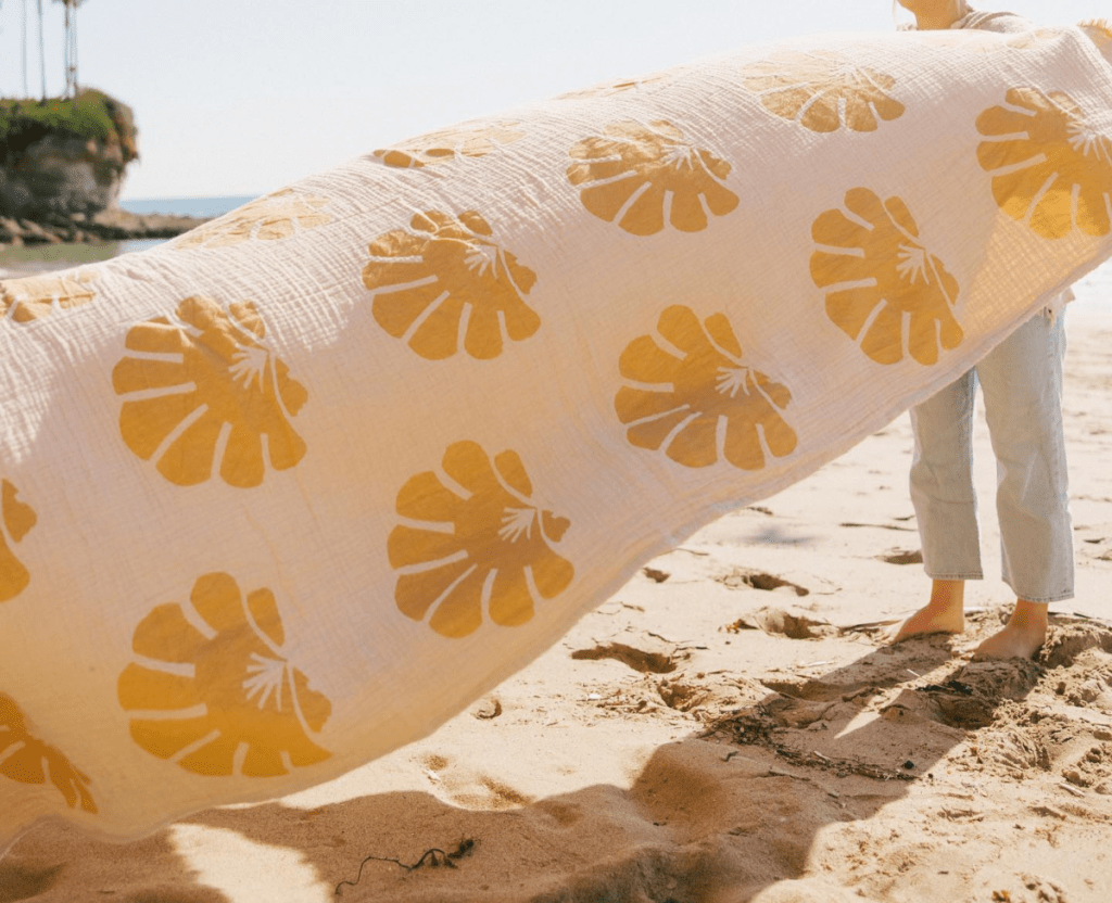 shaking sand from a yellow and white beach towel