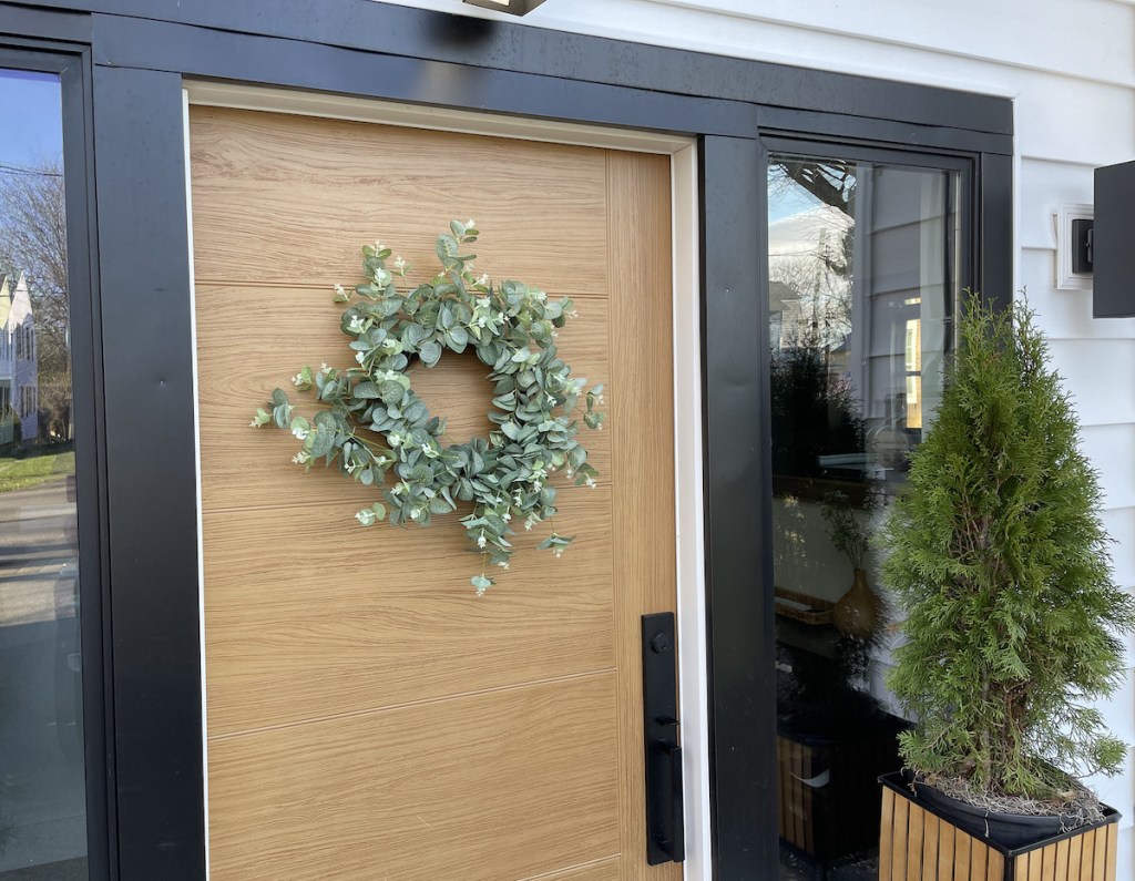 green wreath hanging on modern door - best fake plants