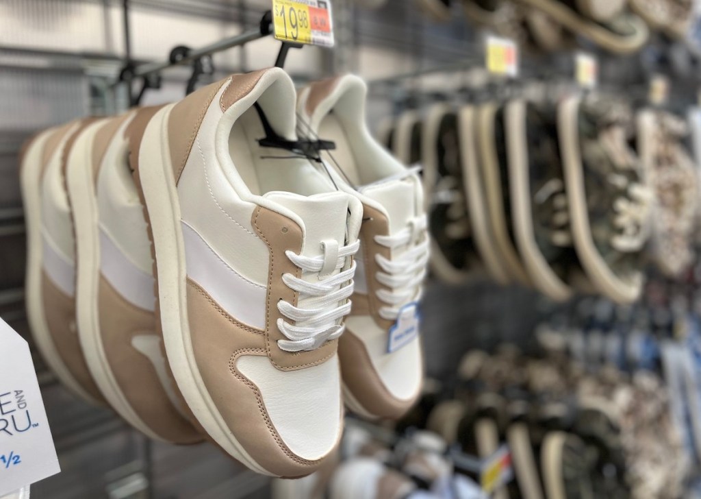 pair of white and tan trainer sneakers hanging on store shelf