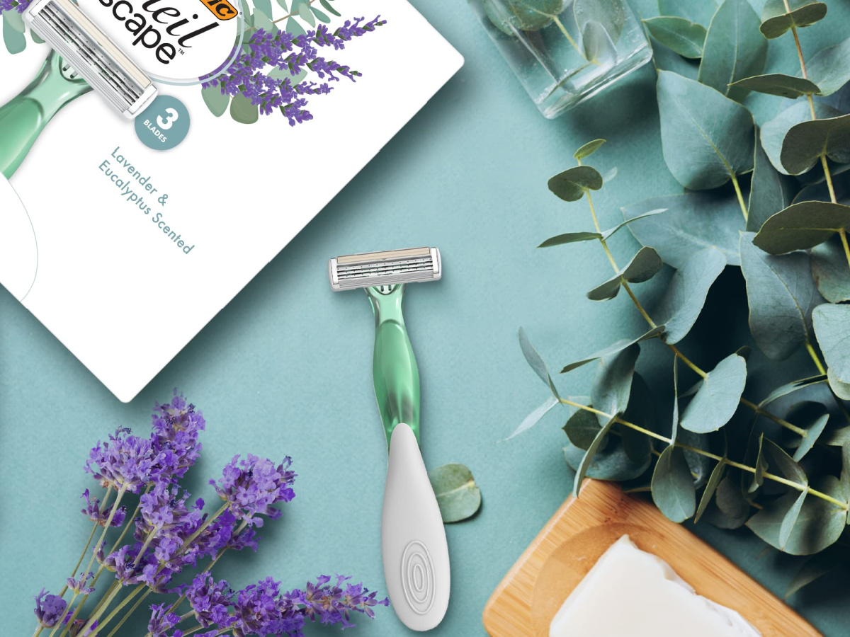 Bic Soleil Escape razor box and razor on green surface with flower scattered about