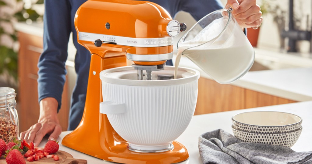 pouring milk into a kitchenaid ice cream attachment on an orange mixer