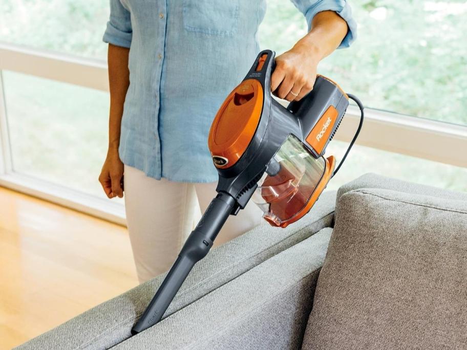 woman using handheld vacuum to clean couch