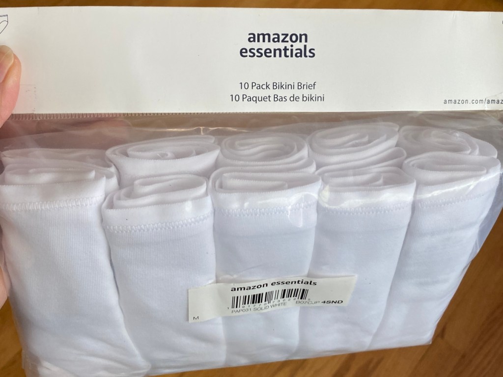 holding a 10-pack of white bikini briefs