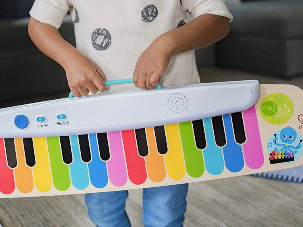 child carrying baby Einstein wooden keyboard