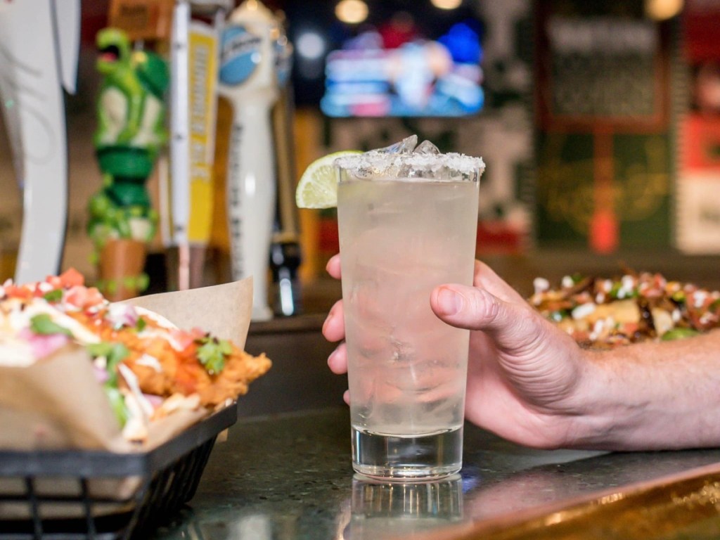 holding a margarita in a tall glass 