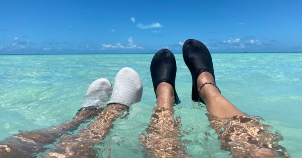 two pairs of water shoes on feet in the ocean