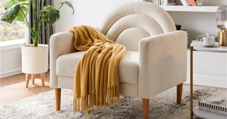 large off white modern style accent chair with a yellow throw blanket on it in a living room