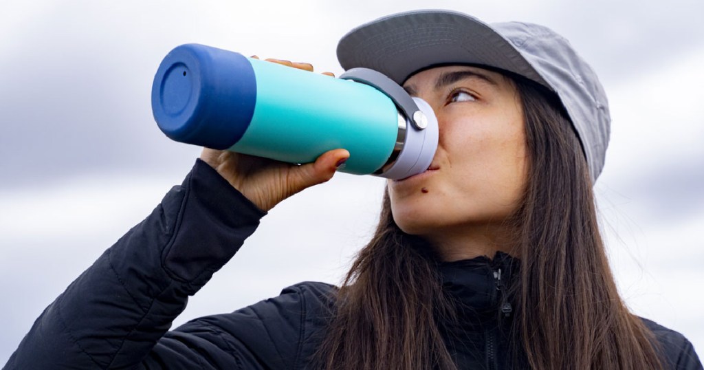 woman drinking from blue water bottle
