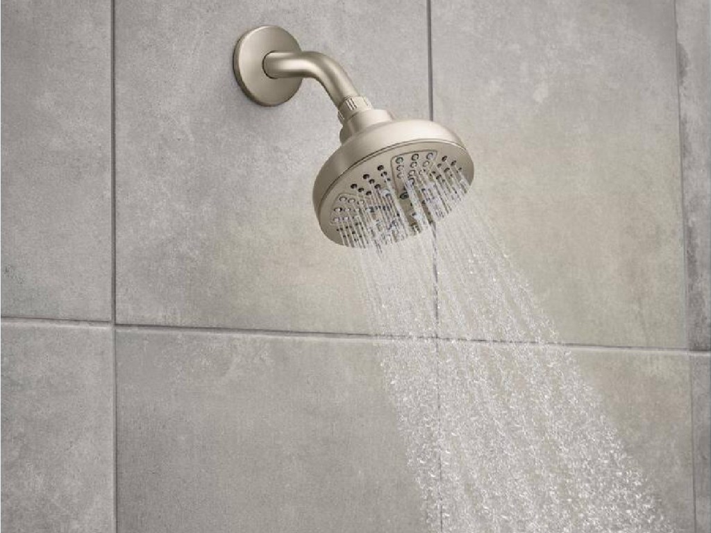 Showerhead fixture with water running out of it in the shower