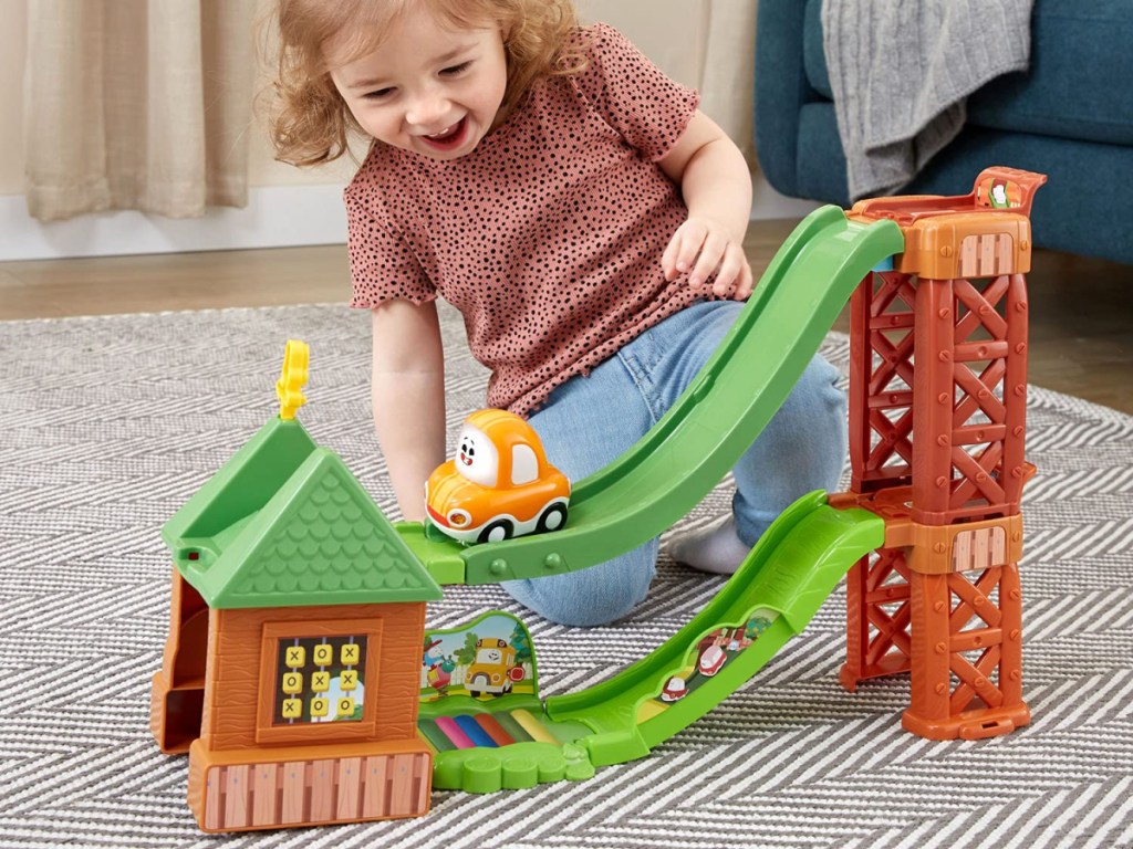 girl playing with playground playset on floor